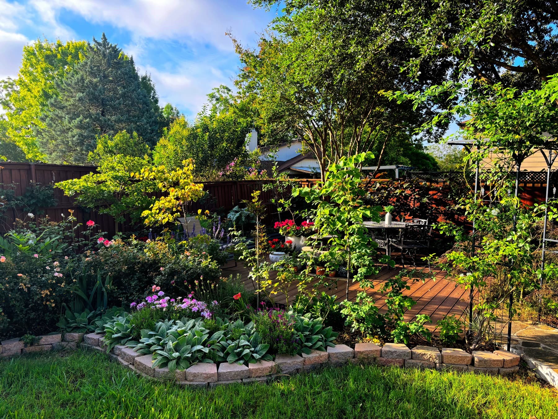 The same yard reimagined as a deck garden room full of flowers