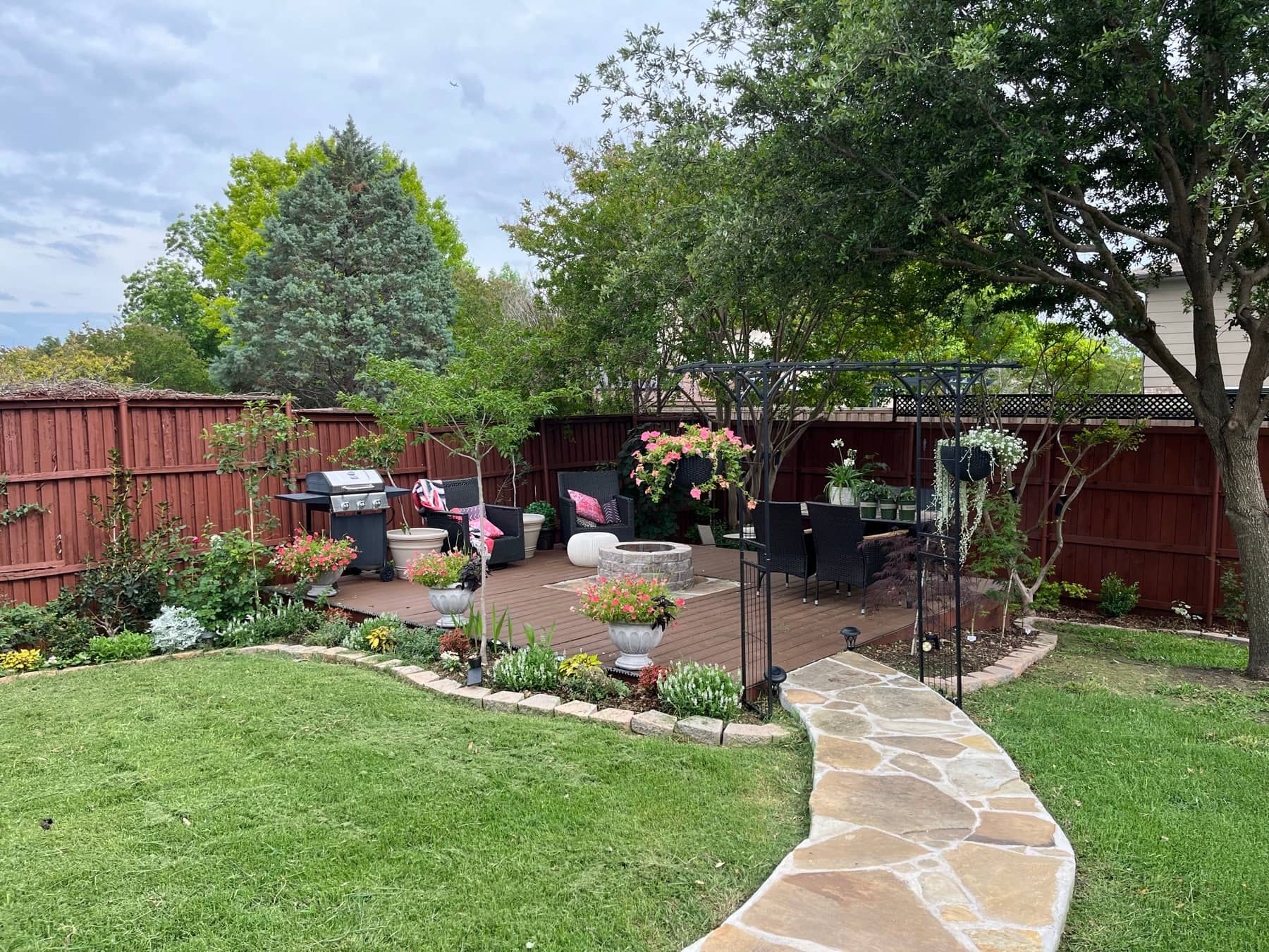 A flagstone path curving across a green lawn to a planted patio